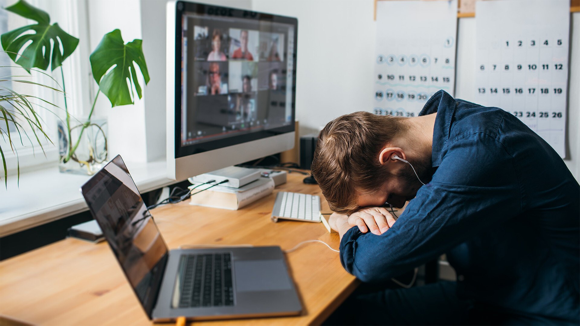 A person rests their head on the desk during a meeting. 