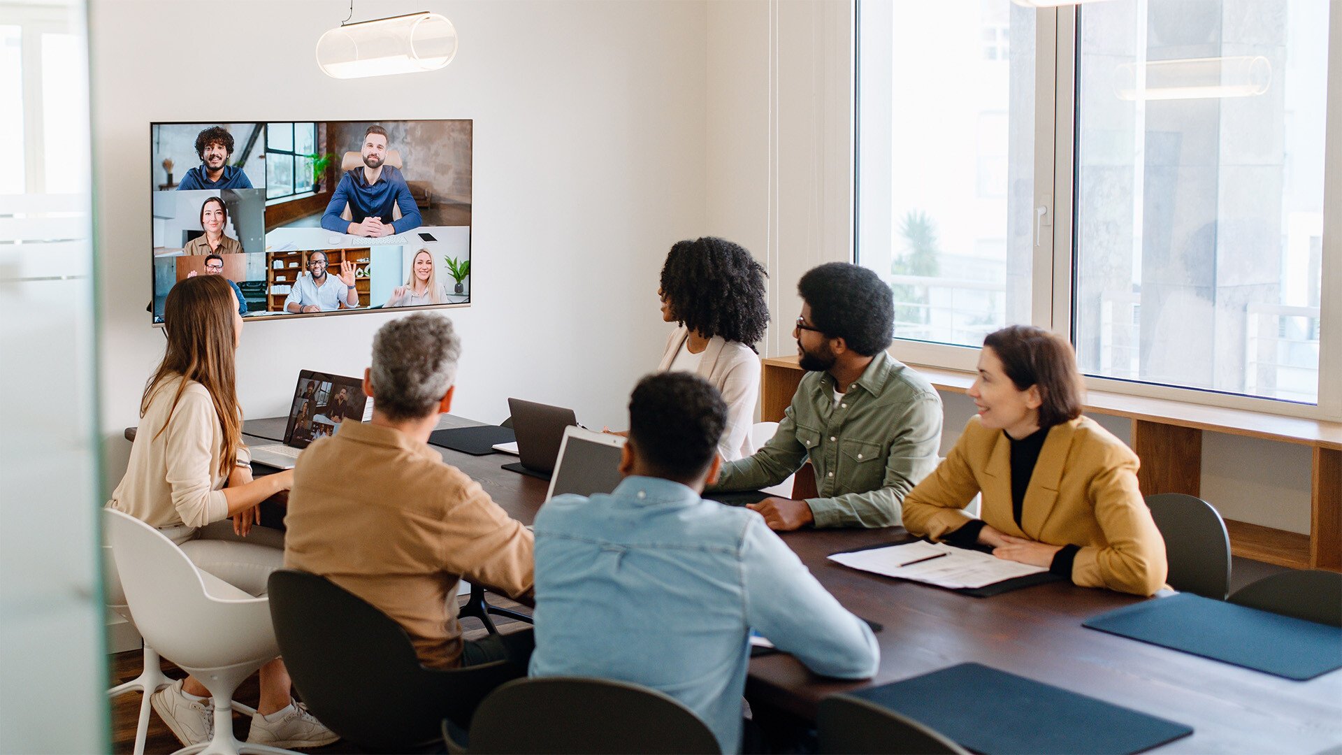 Employees sit around a conference table and join a virtual training. 