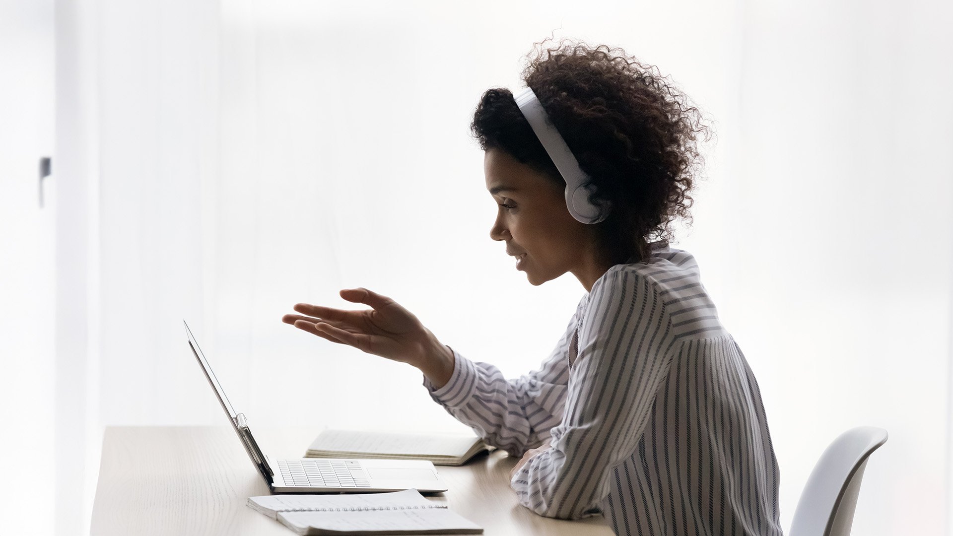 A person explains their point while on a virtual call in a white room